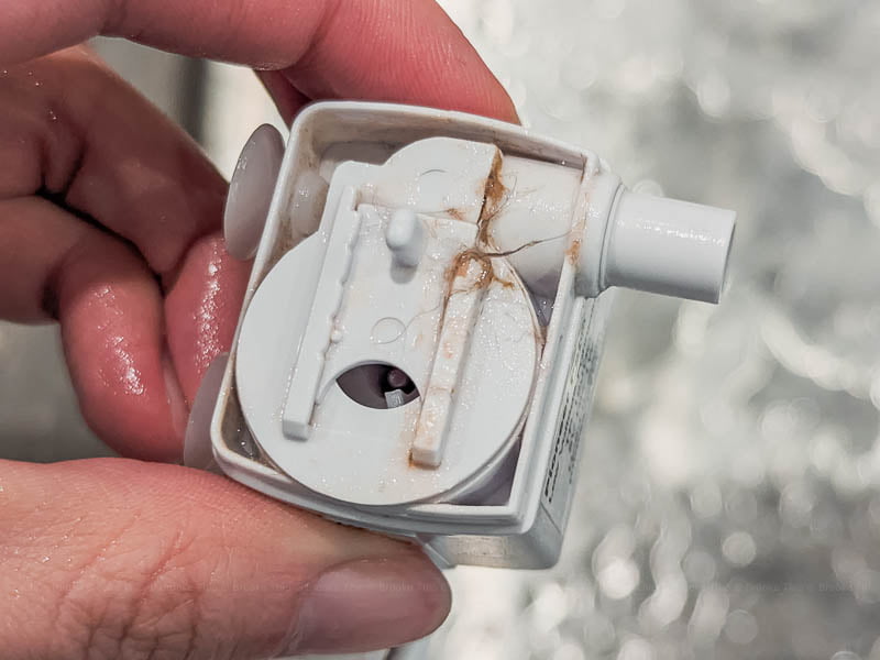 A pet fountain pump with front cover removed, showing the dirt and gunk inside.